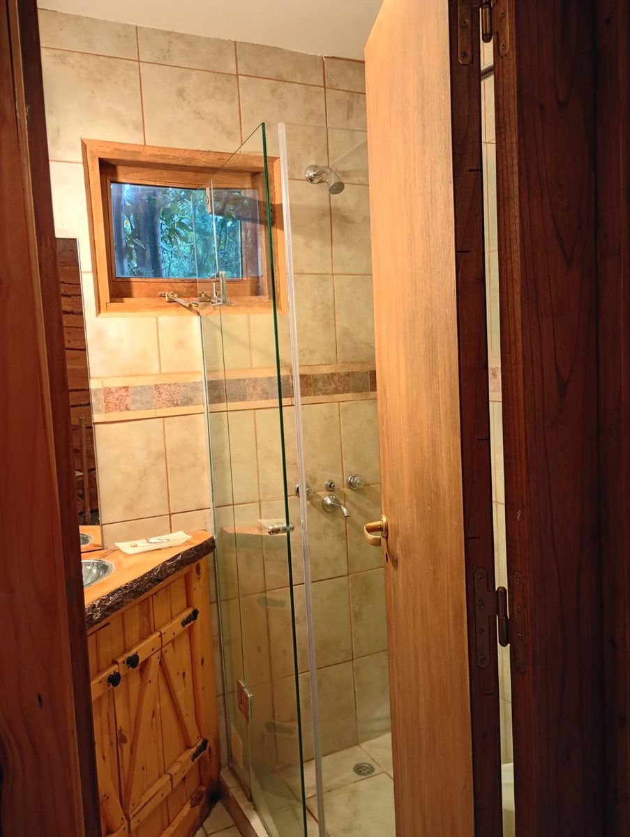Baño privado de la cabaña con ducha vidriada y bacha de madera