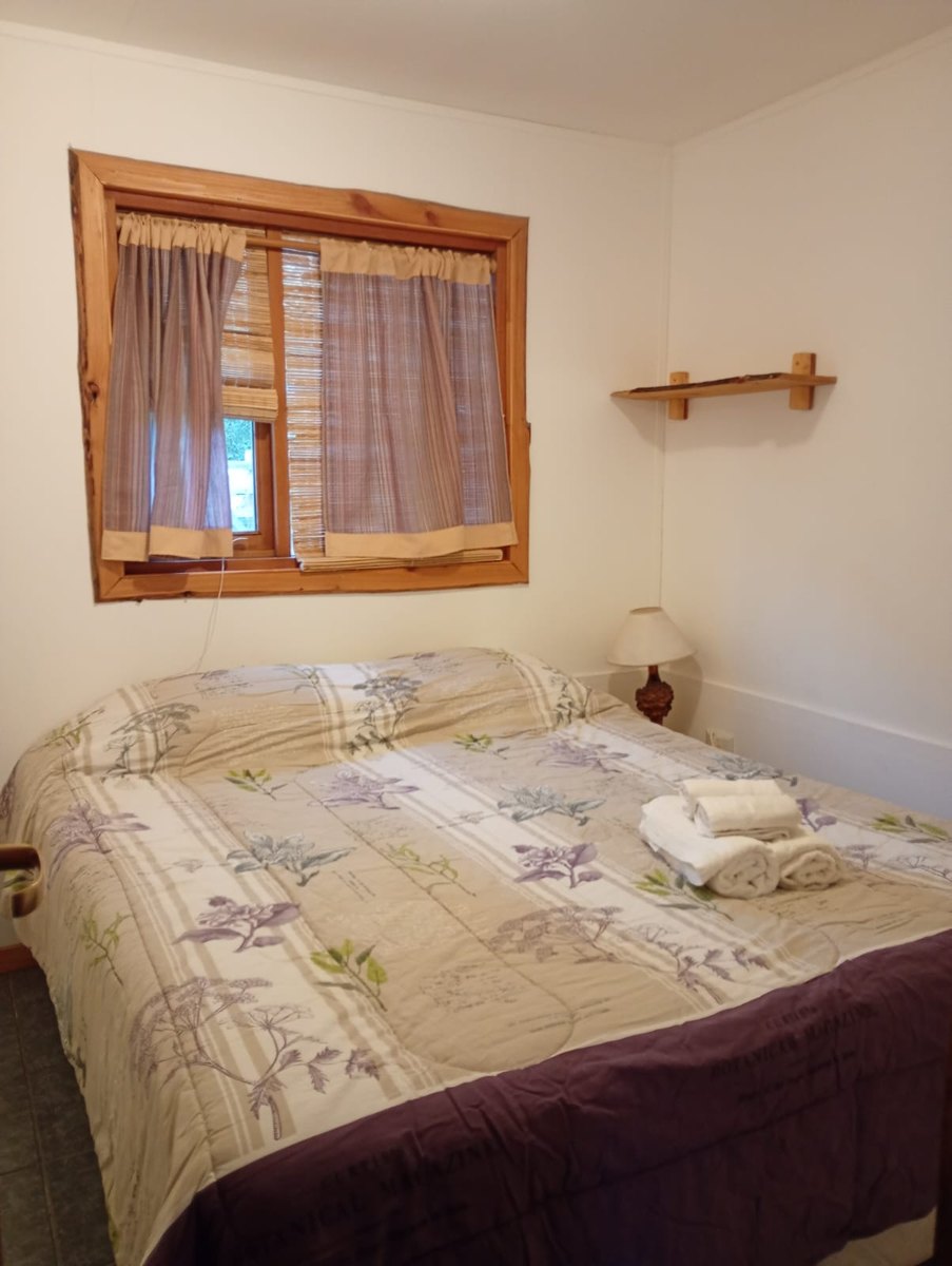Dormitorio de la cabaña con cama de dos plazas y toallas dobladas