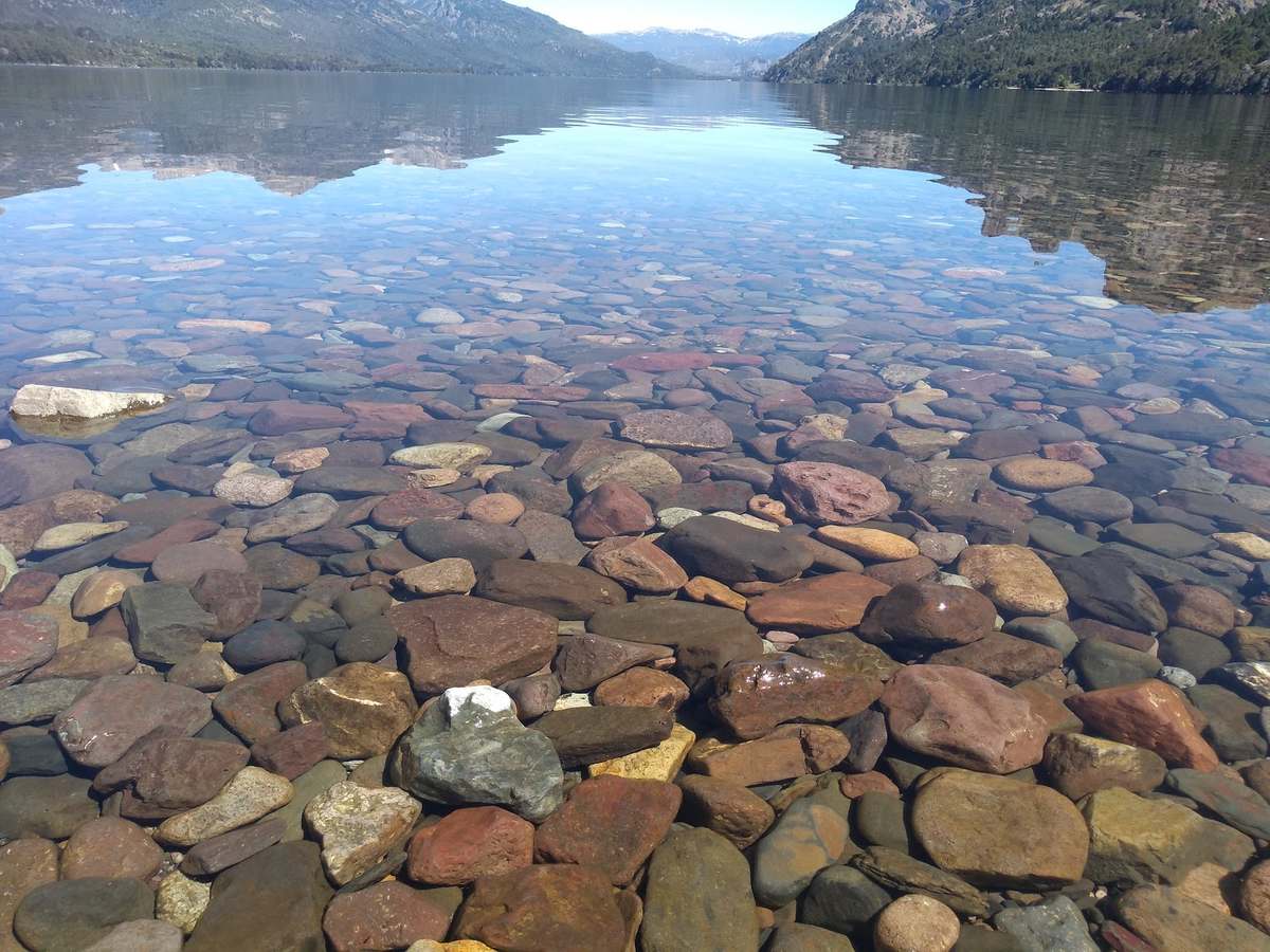 La orilla del lago con las piedras bajo el agua transparente