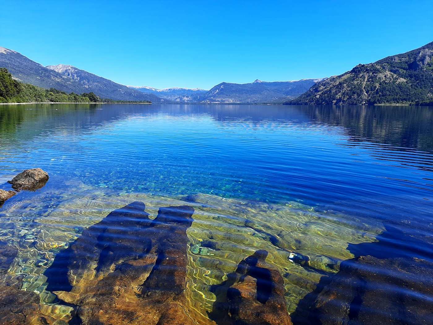 El lago Meliquina con el agua transparente y las montañas de fondo