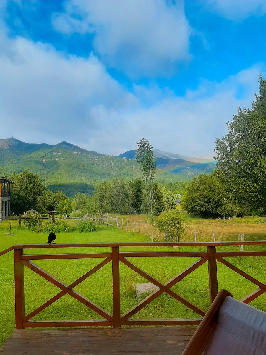 La vista desde el deck de la cabaña, con el parque, las montañas y un arcoíris